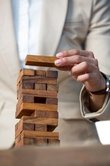 Businesswoman placing wooden block on a tower