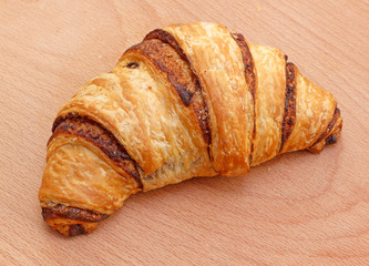 Fresh chocolate croissant on wooden background