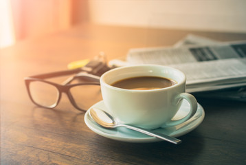 Newspaper reading glasses coffee cup and mobile phone on busines