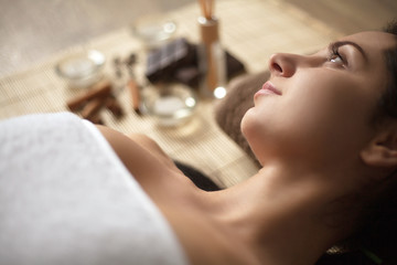 Young woman lay on spa bed with spa ingredients and materials