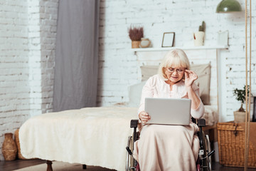 Pleasant disabled aged woman using laptop