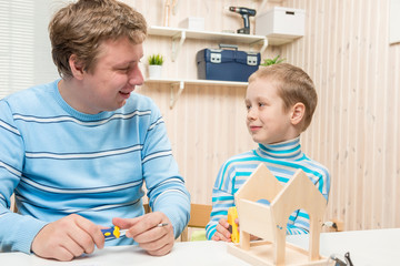 Obraz premium father and son preschooler build a wooden bird feeder