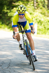 Naklejka premium professional sport Cyclist riding a bike on an open road down the hill on a hot summer day
