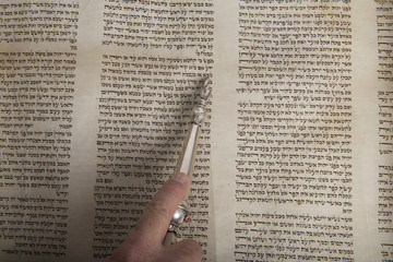 hand of a man reading an ancient torah scroll