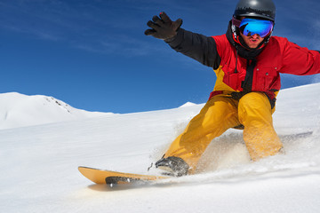 Snowboarder riding fast on dry snow freeride slope.