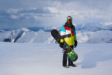Snowboarder holding snowboard in hand standing in the snowfall