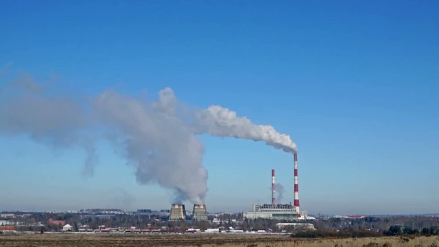 Thermal power plant or a factory with Smoking chimneys on the horizon. Polluting smoke into the clear blue sky.