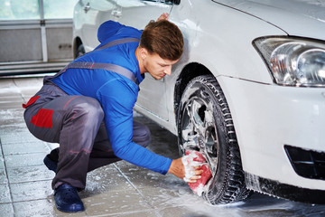Fototapeta na wymiar Man worker washing car's alloy rims on a car wash