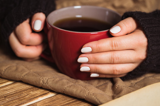 Woman with beautiful manicure holding a red cup of tea