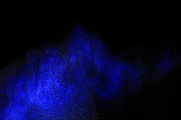 Freeze motion of blue powder exploding, isolated on black, dark