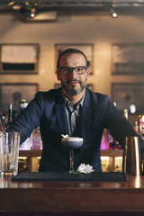 Barman is making cocktail at night club.