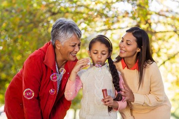 Multi-generation family blowing bubbles at park