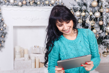 attractive young woman using tab in christmas interior