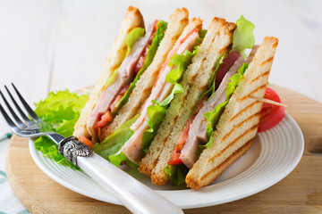 Sandwich for breakfast with stuffed tomatoes with ham and lettuce on a light wooden background. Selective focus.