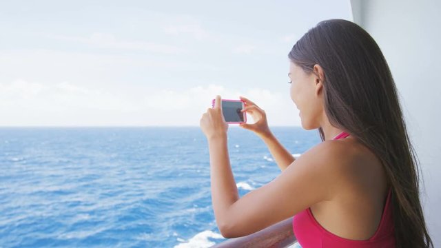 Cruise ship vacation woman taking photo with smart phone camera enjoying travel at sea. Girl using smartphone to take picture of ocean. Woman in dress on luxury cruise liner boat. RED EPIC SLOW MOTION