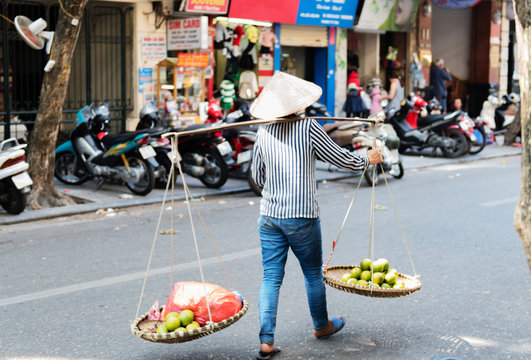 vietnamesische Frau trägt Körbe mit Obst und Gemüse auf der Straße in Hue, Vietnam 