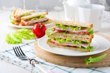 Sandwich for breakfast with stuffed tomatoes with ham and lettuce on a light wooden background. Selective focus.