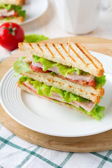 Sandwich for breakfast with stuffed tomatoes with ham and lettuce on a light wooden background. Selective focus.