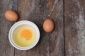 Raw egg in a bowl selective focus on wooden table, Top view 