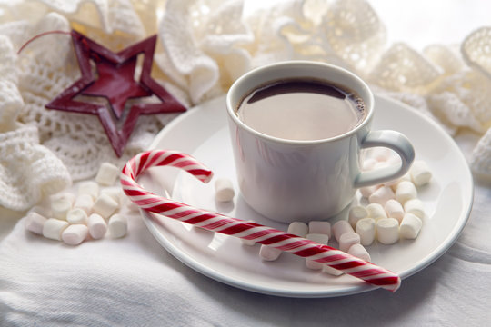 white Cup of cocoa on a saucer, marshmallows and  candy