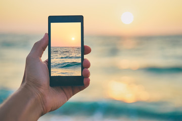 Cell technology and vacation. Close up of male hand holding smartphone, taking picture of sea...