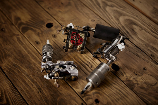 Three custom made professional induction tattoo machines arranged in round on a brown wooden table