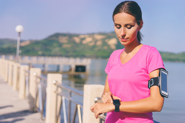 Healthy lifestyle and technology. Pretty young woman using smart watch tracker near the sea.