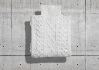 Turtleneck cotton cableknit white warm sweater neatly folded isolated on industrial concrete background