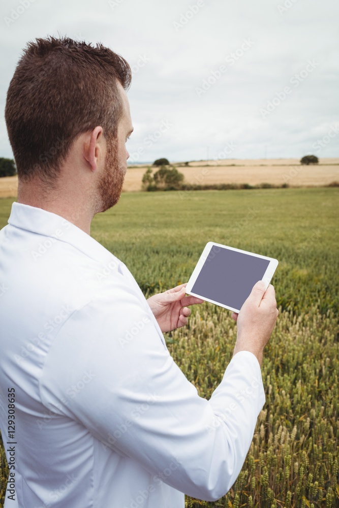 Poster agronomist using digital tablet in the field