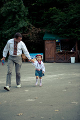 Happy dad walks with his little daughter in red wreath