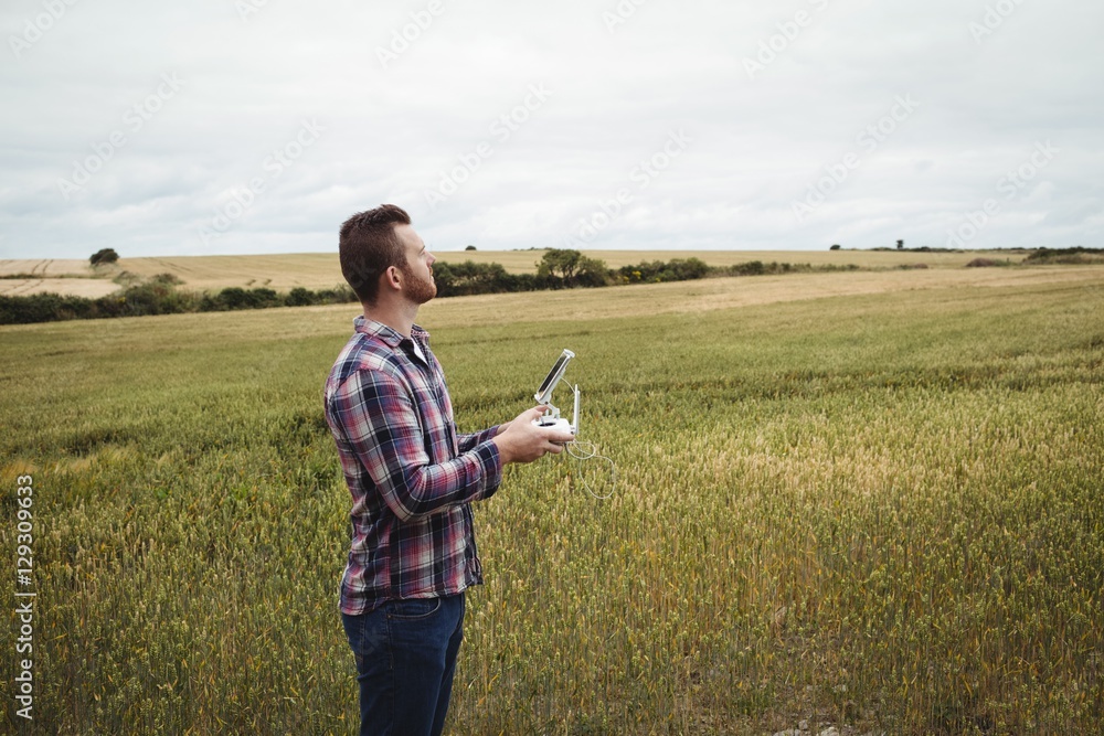 Poster Farmer using agricultural device while examining in field