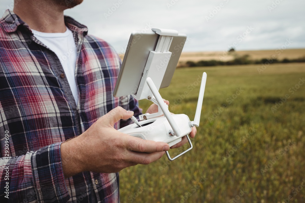 Poster Farmer using agricultural device while examining in field