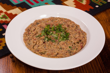 Bean porridge with parsley in a white plate on a wooden table