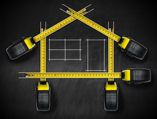 House project concept. Tape measures in the shape of house on a blackboard with white drawing