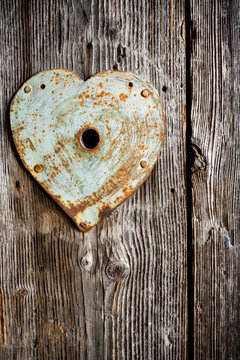 Rusty trim on keyhole as heart on old wooden door. Vertical shot
