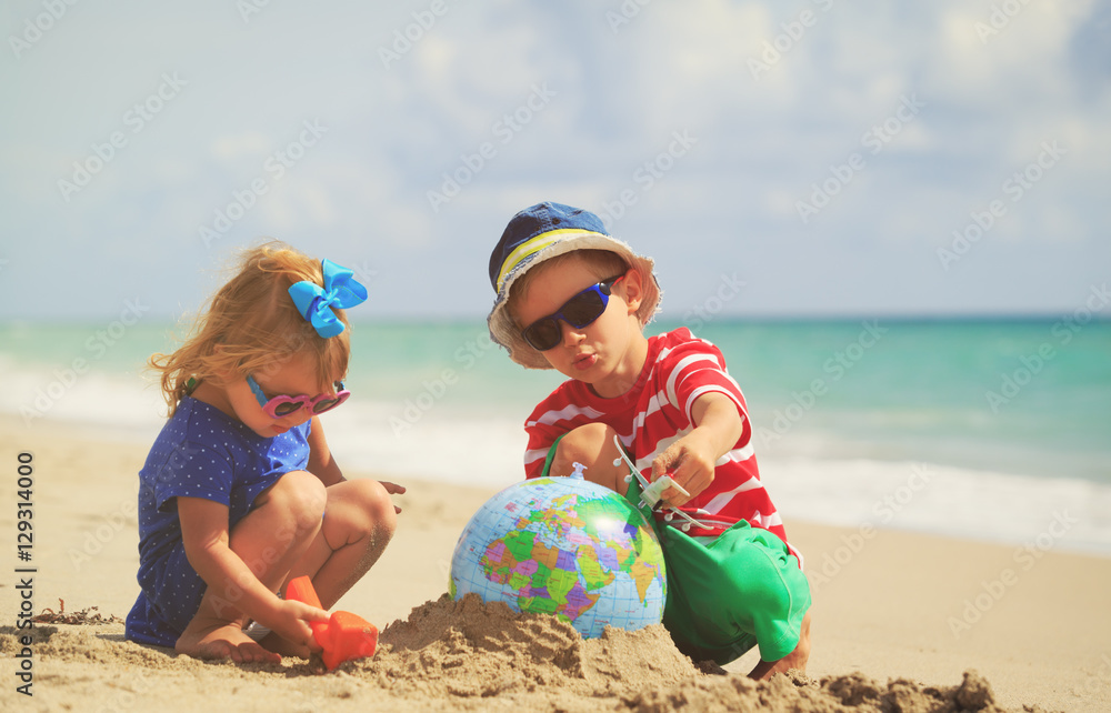 Wall mural kids play with globe and toy plane on beach