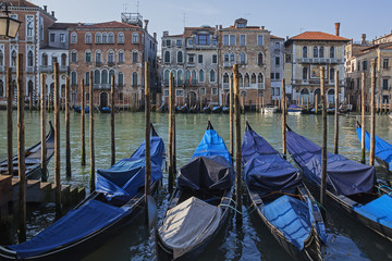 Fototapeta na wymiar Gondolas anchored at wooden piles on Grand Canal in the Venice 
