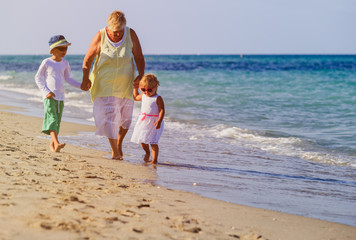 Happy grandmother with kids- little boy and girl- at beach