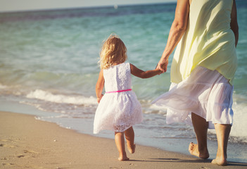 Happy grandmother with little girl walk at beach