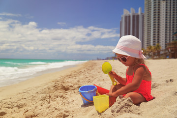 Fototapeta na wymiar little girl play with sand on beach