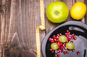 fitness background with lemon, grapes, apple, pomegranate and centimeter/fitness concept with lemon, grapes, apple, pomegranate and centimeter