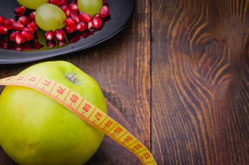 fitness concept with apple, pomegranate, grapes and centimeter/fitness background with apple, pomegranate, grapes and centimeter