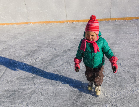cute little girl learning to skate in winter