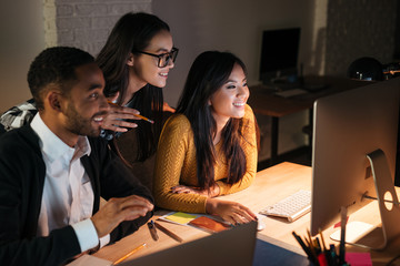 Cheerful business people working late at night in their office