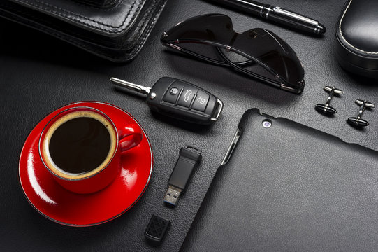 Man Accessories In Business Style With Cup Of Coffee, Gadgets, Car Key, Cufflinks, Sunglasses, Briefcase And Other Luxury Businessman Attributes On Leather Black Background, Fashion Industry