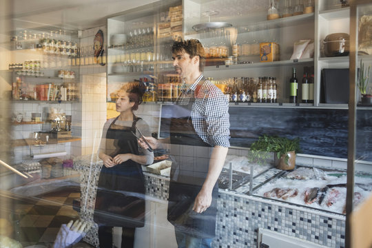 Owners Working In Fish Store Seen Through Glass