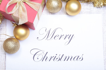 Text merry christmas on paper with balls and gift box
