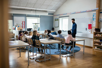 Confident teacher teaching students in classroom at school
