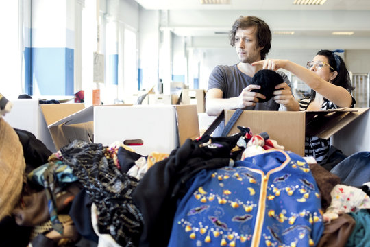 Mature woman guiding volunteer while checking clothes at workshop
