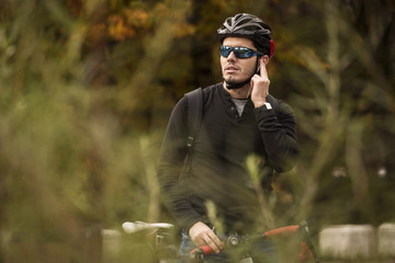 Man with his bike talking on handsfree, in the middle of nature